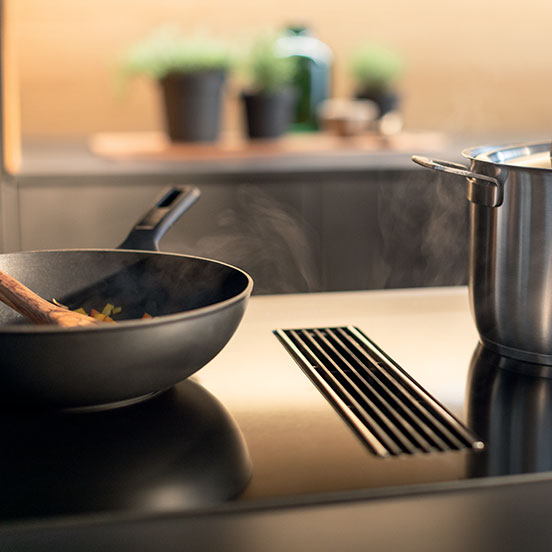 Faber black hob extractor with fumes coming from a pad and a pot